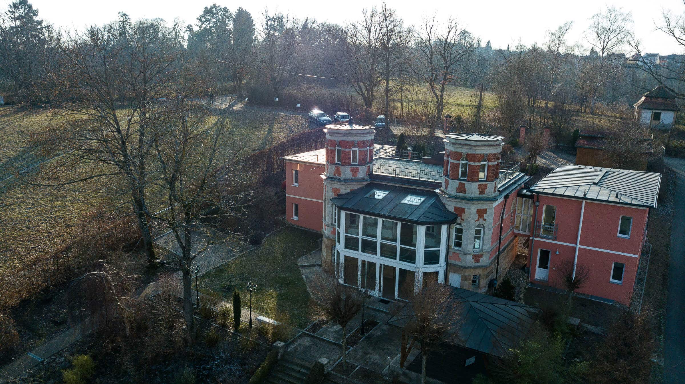 Luftaufnahme einer historischen Villa mit zwei Türmen und Wintergarten im Grünen bei Bamberg